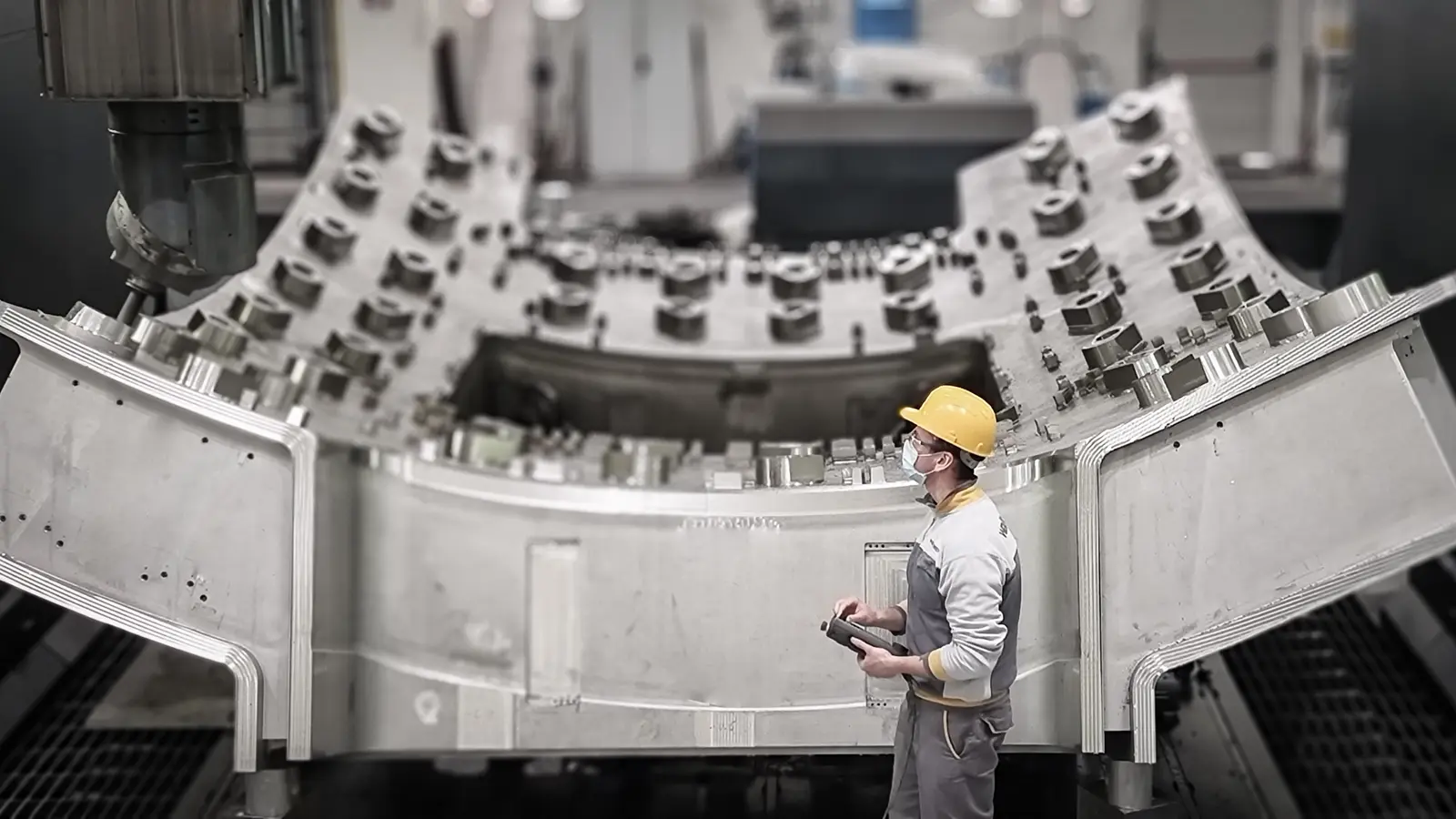 Worker standing beside a large ITER vacuum-vessel sector during manufacturing